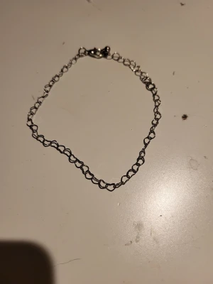 Tunt silverfärgat kedjearmband - Säljer ett tunt armband i silverfärg med små hjärtformade länkar. Armbandet har ett enkelt spänne och passar perfekt för dig som gillar minimalistiska smycken. Stilren design som är lätt att matcha med andra accessoarer.