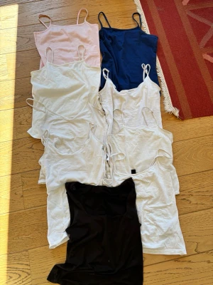 Nio baslinnen i olika färger - Säljer ett paket med nio linnen i olika färger: vitt, svart, marinblått och ljusrosa. Alla har smala axelband och enkel, klassisk design. Perfekta att matcha till olika outfits och funkar året runt. En för 30