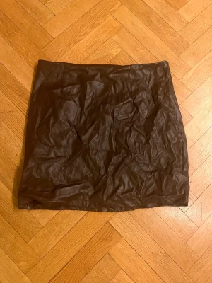 Brun kortkjol i skinnimitation - Snygg brun kortkjol i skinnimitation med enkel och rak passform. Kjolen har en slät yta och är perfekt för dig som vill ha en trendig och stilren look. Passar till många olika outfits och är lätt att matcha.Skriv gärna för mått! 💕