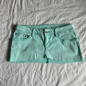 Turkos kort jeanskjol - Midjemått rakt över: 39 cm längd: 20 cm