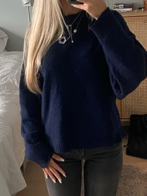 Mörkblå stickad tröja från Nelly - Mysig mörkblå stickad tröja från Nelly med avslappnad passform och långa ärmar. Tröjan har ribbade muddar vid ärmslut och nederkant, perfekt för lager på lager och en chill look. Enkel att matcha med jeans eller kjol. 