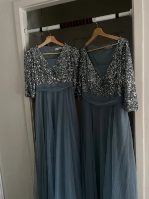  långklänningar så finna och fest klänning  - Säljer två eleganta långklänningar i ljusblått med glittrig silverpaljett upptill och v-ringad hals. Kjolen är i tunn, svepande tyll och klänningarna har halvlånga ärmar. Perfekt för bal eller fest.