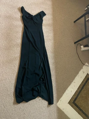 Grön långklänning med slits  - Super snygg långklänning med en slits, passar bra till t.ex bröllop eller bal, säljer pga den kommer inte till användning 