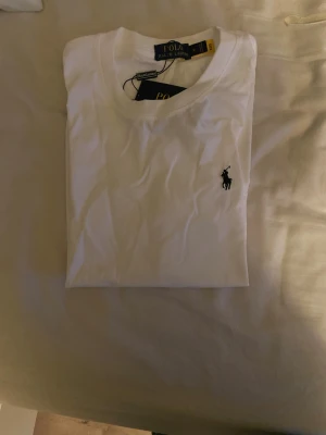 Vit polo Ralph lauren t shirt - Säljer nu en polo Ralph lauren t shirt, helt oanvänd med lapparna kvar. Fraktar inom 1 dags - kan mötas.   Riktigt snygg och stilren perfekt nu till våren och sommaren, ger ett fint helhets intryck. Vid frågor eller liknande kontakta mig, vänlig hälsning!