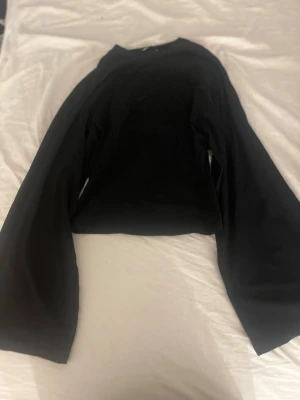 Svart tröja från 157 med vida ärmar - Säljer en svart tröja från 157 med rund hals och vida ärmar. Tröjan har en enkel och clean design som passar till det mesta. Materialet känns mjukt och bekvämt, perfekt för dig som gillar minimalistisk stil.