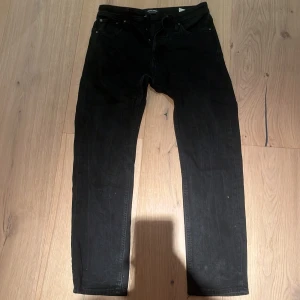 Svarta jeans från Jack & Jones - Svarta jeans från Jack & Jones med modellen Tapered/Mike. Klassisk femficksdesign och rak passform som smalnar av nedtill. Perfekta för en stilren look och enkla att matcha med olika outfits.