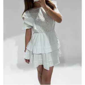 Vit volangklänning med broderade detaljer - Fin klänning med volanger, aldrig använd.                                 Storlek M/L den var lite kort på mig som är 176 cm