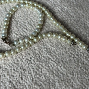 Klassiskt pärlhalsband - Elegant halsband med vita pärlor och silverfärgade detaljer vid låset. Perfekt accessoar för att lyfta din outfit med en tidlös och stilren känsla.