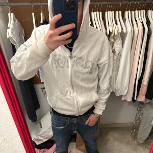 Black Squad zip up - Säljer en vit hoodie från Black Squad i oversized fit. tryckt logga på bröstet och detaljer längs ärmarna.