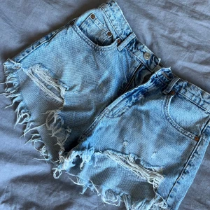 Jeansshorts från Zara - Säljer ett par ljusblå jeansshorts från Zara med fransade kanter och klassisk femficksdesign.Perfekta för varma dagar.🩵💕