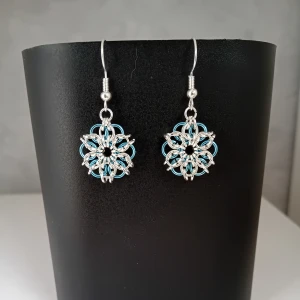 Egentillverkade örhängen  - Egentillverkade örhängen gjorda med bindringar i blå och silverfärg. Längd ca 3cm långa. Blomman är ca 2cm lång. Öronkroken är nickelsäker och aldrig använda.