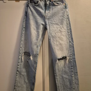 Ljusblå slitna jeans från Perfect Jeans - Ljusblå jeans med raka ben och slitningar vid knäna från Perfect Jeans. Klassisk femficksmodell med hög midja och avslappnad passform. Perfekta för en avslappnad och trendig look.