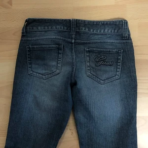 Supersöta mörkblå jean från Guess - Storlek 25  Innerbenslängd:73 cm Midjemått:35 cm Flare/bootcut.  Säljer ett par mörkblå jeans från Guess med broderad logga på bakfickan. Byxorna har klassisk femficksdesign, låg midja och bootcut-stil. Perfekta för dig som gillar en tidlös look med lite utsvängda ben.