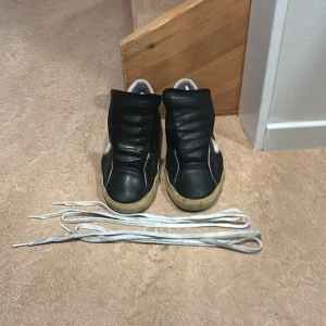 Svarta sneakers med vita detaljer - Svarta sneakers med vita detaljer och vit sula. Skorna har rund tå och platt sula. Medföljer vita skosnören. Ovandelen är i skinn och syntet, med silverfärgad detalj vid hälen. Perfekta för en avslappnad stil. Priset kan diskuteras vid snabb affär👍💸💵