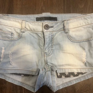 Ljusblå jeansshorts från ONLY - Säljer ett par ljusblå jeansshorts från ONLY med slitna detaljer framtill och klassiska fickor både fram och bak. Shortsen har låg midja och är perfekta för varma dagar. Snygg, avslappnad look med råa kanter. W28 och allmänt bra 💞