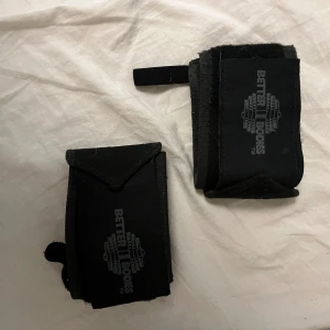 Svart tränings utrustning från Better Bodies - Säljer 2 stycken vet inte vad det är men har använt som ankle straps från Better Bodies. Dom är breda och har kardborreknäppning för enkel justering. Perfekt för gym och styrketräning. Logga på framsidan.