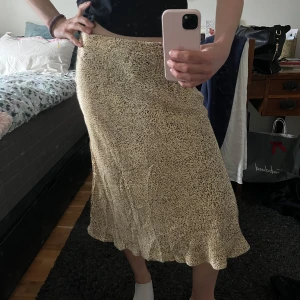 Silkeskjol  - Guldig, glansig kjol i silkeslent material. Jattefick skick, aldrig anvand. Sma leoparddetaljer, supersot nar man ska va lite extra fin. 35 cm rakt över, men en stretchig resár i midjan! Hör av dig vid frägor.