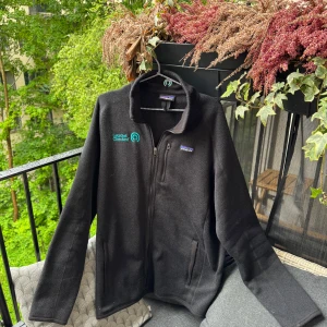 Patagonia Fleece jacka - Grymt snygg och trendig modell på jacka! Denna modellen har företags loggor bak och fram, i mina ögon gör dessa loggor jackan Snyggare!   •Skick:8.5/10 delvis nopprig, inga hål eller fläckar  •storlek📏: L-XL, den har Längden av en L och bredden av XL   •Nypris/Butikspris:💰 ~1899kr   Köp gärna i bundles för att underlätta i frakt och på detta vis blir jag mer flexibel i pris! Våga buda! 🚚🤝