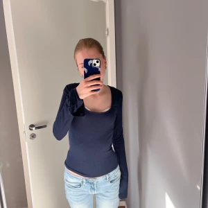 Mörkblå långärmad topp med rund hals - Säljer en enkel och stilren mörkblå långärmad topp med rundad halsringning. Toppen är figurnära och passar perfekt till jeans eller kjol. Mjukt och stretchigt material som är skönt mot huden.
