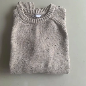 Beige stickad tröja - Säljer en stilren beige stickad tröja med rund halsringning och ribbade muddar. Perfekt för lager-på-lager och passar till många olika outfits. Enkel och tidlös design.