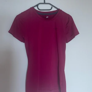 Mörkrosa sportig t-shirt från Peak Performance - En enkel och sportig mörkrosa t-shirt från Peak Performance. Modellen är tight med rund halsringning och korta ärmar. Perfekt för träning eller en aktiv vardag. Snygg och stilren design utan mönster.❤️