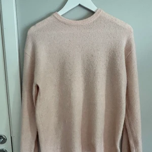 Ljusrosa stickad tröja från H&M - Mysig ljusrosa stickad tröja från H&M med rund halsringning och långa ärmar. Perfekt för lager-på-lager och enkel att matcha med olika outfits. Säljes då den inte längre används.