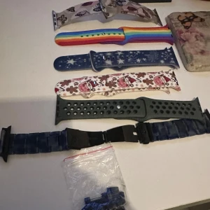Flera utbytbara klockarmband till smartklocka - Säljer ett gäng olika klockarmband till smartklocka. Här finns bland annat armband med julmönster, regnbågsfärger, blått med snöflingor, svart med hål och ett blått metallarmband. Perfekt för dig som vill variera stilen på din klocka.