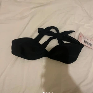 Svart bikiniöverdel från Nelly - Säljer en svart bikiniöverdel från Nelly i modellen 'Open Mind'. Överdelen har knyt i nacken och en enkel, stilren design. Perfekt för sommardagar vid stranden eller poolen. Storlek XS.