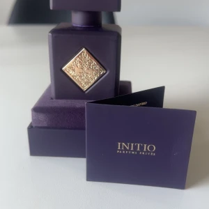 Initio Side Effect Eau de Parfum 90ml - Exklusiv parfym från Initio Parfums Privés i en mörklila, fyrkantig flaska med guldfärgad detalj och lock. Flaskan har en lyxig känsla och levereras i matchande ask. Doften heter Side Effect. OBS FINNS KVITTO