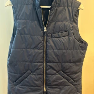 Blå dunväst från Stenströms - Snygg blå dunväst från Stenströms med dragkedja framtill och tre fickor. Västen har en quiltad design och är perfekt för lager-på-lager-stil. Passar dig som vill ha en klassisk och stilren look.