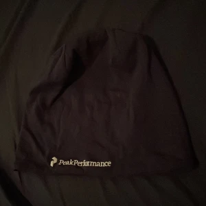 Svart mössa från Peak Performance - Säljer en svart mössa från Peak Performance med logga broderad framtill. Enkel och stilren design, perfekt för kyliga dagar.