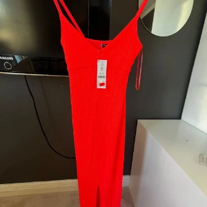 Röd Livia klänning med smala axelband - Säljer en eldigt röd långklänning från Livia med smala axelband och stretchigt material. Klänningen har en enkel, tight passform och är perfekt för dig som vill sticka ut. Supersnygg till sommarens alla tillfällen!