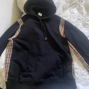 Svart hoodie från Burberry  - Säljer en svart hoodie från Burberry då den aldrig kommer till användning, den är i storlek XL passar lika bra som L. 