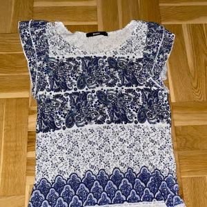 Vit och blå mönstrad topp från BikBok - Supersöt topp från BikBok i vitt och blått med paisleyinspirerat mönster och småblommiga detaljer. Modellen är ärmlös med rund hals