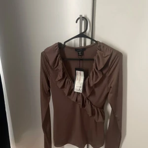 Brun volangblus  - Supersnygg brun blus från Amisu med v-ringning och volangdetaljer. 😊fint skick och helt oanvänd 💕passar bäst för folk i storlek S