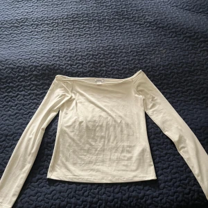 Vit offshoulder topp från Monki - Säljer en stilren vit offshoulder topp från Monki i storlek S. Toppen har långa ärmar och en tight passform som sitter snyggt över axlarna. Perfekt att styla med jeans eller kjol för en clean look.