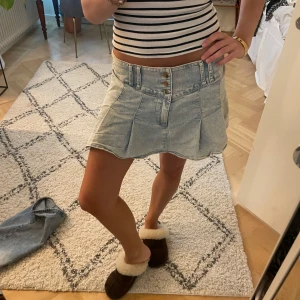 Ljusblå jeanskjol med knappar - Säljer en ljusblå jeanskjol med tre snygga knappar framtill och bred linning. Kjolen har en kort och lätt utsvängd modell med markerade sömmar och fickdetaljer. Perfekt för dig som gillar en chill och trendig stil. 🩷🩷🩷 