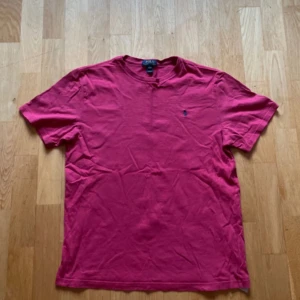 Rosa t-shirt från Polo Ralph Lauren - Säljer en klassisk rosa t-shirt från Polo Ralph Lauren i storlek S.Tröjan är i storlek XL men den passar suveränt som storlek S T-shirten har korta ärmar, rund halsringning och den ikoniska broderade loggan på bröstet. Tillverkad i mjuk bomull för en skön känsla hela dagen.