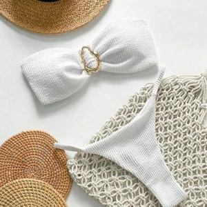 Vit bandeau bikini med gulddetalj - Superfräsch vit bandeau bikini med snygg guldfärgad ring i mitten på överdelen. Bikinin har ribbad struktur och smala axelband på underdelen. Perfekt för stranden eller poolen!