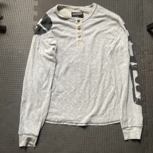 Grå långärmad tröja från GASP - Säljer en grå långärmad tröja från GASP med svarta tryckdetaljer på axel och ärm. Den är gjord av bomull och sitter riktigt fint när man ska gymma eller bara använda vanligt. Använt 1 gång. Pris kan diskuteras 