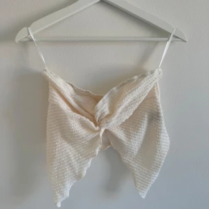 Beige croppad linnetopp från SHEIN - Aldrig använd.  cremefärgad croppad topp  i storlek M. Toppen har tunna axelband, ribbad struktur och en snygg omlott-detalj framtill. Materialet är mjukt och lätt. nederkant ger en cool och trendig vibe.