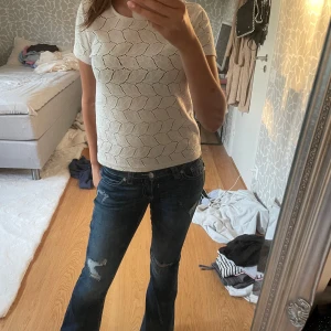 Vit stickad topp från Jacqueline de Yong - Säljer en vit stickad topp från Jacqueline de Yong i storlek XS. Toppen har korta ärmar och ett snyggt hålmönster med bladliknande former. Perfekt till jeans eller kjol för en fräsch och stilren look.