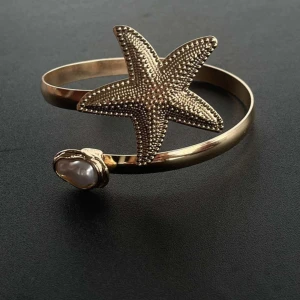 Guldigt armband med sjöstjärna och pärla - Unikt armband i guldton med en stor, detaljerad sjöstjärna och en vit pärla. 🩷🪷🤗