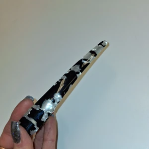 Svart -silvrig mönstrad klämma  - Snygg svart- silvrig Hårklämma i mönster. Hårklämman har en glansig finish och är gjort i syntetmaterial med metall på insidan för extra stadga. Perfekt accessoar för att lyfta din look och hålla håret på plats.