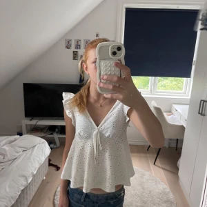 Vit blus med volangärmar och knyt - Supersöt vit blus med broderade hål och volangärmar. Prislapparna är borta så vet inte vart den kommer ifrån! Tror att stoleken är runt S-XS💕