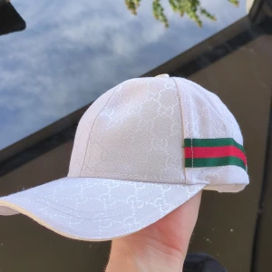 VIT GUCCl KEPS MED MONOGRAM - Tvär fet keps som passar perfekt till sommaren, med ett stilrent monogram mönster över hela kepsen.