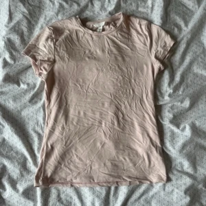 Ljusrosa t-shirt från H&M, M - Säljer en enkel ljusrosa t-shirt från H&M i storlek M. Modellen är klassisk med rund hals och korta ärmar. Materialet är mjukt och stretchigt, tillverkat av polyamid och elastan. Perfekt för dig som gillar basic och stilrena plagg.