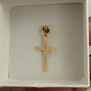 Guld korshänge - Elegant och stilrent korshänge i guld. Perfekt som ett tidlöst smycke att bära till olika tillfällen. Hänget har en enkel och klassisk design som passar alla stilar. 18 karat guld.