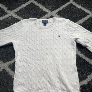 Vit stickad tröja från Polo Ralph Lauren - Säljer en klassisk vit stickad tröja från Polo Ralph Lauren med kabelstickat mönster.  Perfekt nu på våren den har använt 2-3 gånger den är för liten därför jag säljer den. Pris kan diskuteras 