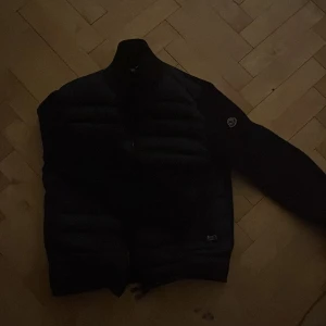 Svart dunjacka från Moncler - Säljer en stilren svart dunjacka från Moncler. Jackan har en quiltad design och långa ärmar. Perfekt för kyligare dagar och ger en snygg look. Kontakta mig för mer info! Den är sunder i fickan och är lite mer som en m än L funkar på båda 